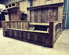 a bed made out of wooden planks in a warehouse area with other wood furniture