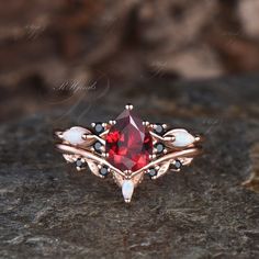 a close up of a ring with a red stone in the middle and white stones around it