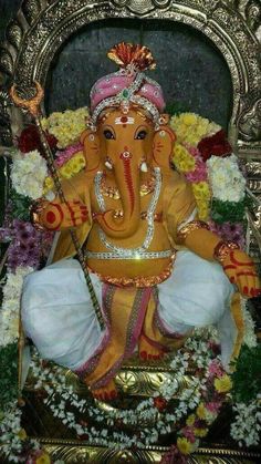 an elephant statue sitting on top of a gold frame with flowers around it's head