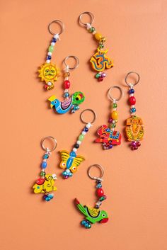 six keychains with different designs on them sitting next to each other against a pink wall