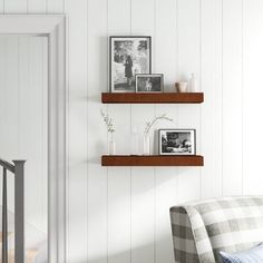 two wooden shelves on the wall above a couch in a room with white walls and wood flooring