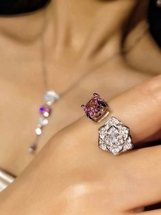 a close up of a woman's hand with two rings on her finger and an engagement ring in the other hand