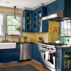 a kitchen with blue cabinets and stainless steel stove top oven, dishwasher, sink, and window