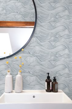 a white sink sitting under a round mirror