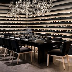 a dining room table with black chairs and a chandelier hanging from the ceiling