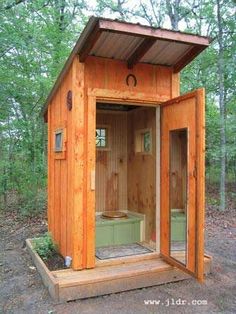 an outdoor sauna in the woods with its doors open and a hot tub inside