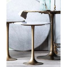 two brass pedestal tables with glass vases on top