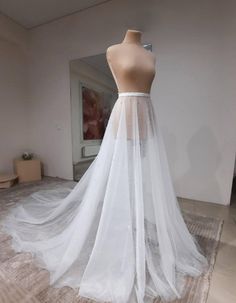 a white wedding dress on display in a room with a mannequin headpiece