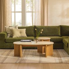 a living room with a green couch and coffee table in front of a large window