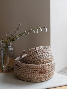 two woven baskets sitting on top of a table next to a vase with flowers in it