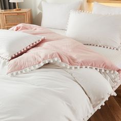 a bed with white and pink pillows on top of it