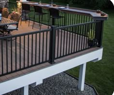 a deck with table and chairs next to an outdoor grill area in the back yard