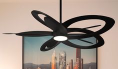 a black ceiling fan hanging from the ceiling in front of a cityscape with skyscrapers