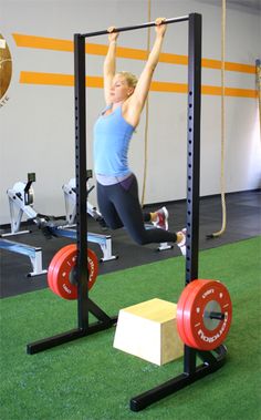 a woman is doing pull ups in the gym with barbells and exercise ropes