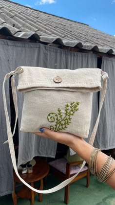 a woman holding up a small bag with flowers on it