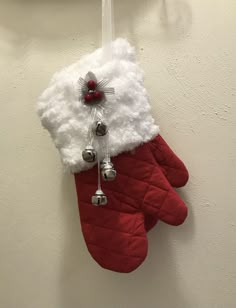 an oven mitt hanging on the wall with bells attached to it and a christmas ornament