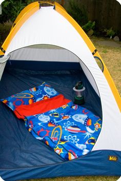 a blue and yellow tent sitting on top of a grass covered field