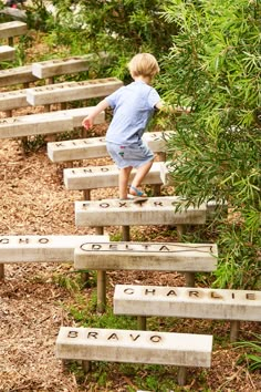 a young boy climbing up the side of a set of stone benches with writing on them