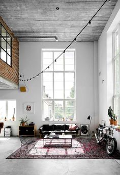 a living room filled with furniture and a large window next to a motorcycle parked in front of it