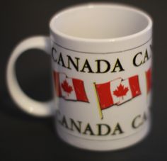 a white coffee mug with the words canada ca and two canadian flags on it's side