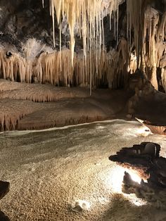 the inside of an ice cave with icicles hanging from it's ceiling and snow on the ground