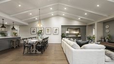 a living room filled with furniture next to a kitchen and dining room table covered in white cloths