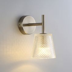 a wall light with a glass shade hanging from it's side on a white wall