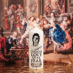 a candle with the words choose love over fear on it in front of a painting