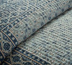 a blue and white bedspread with an intricate design on it's edges