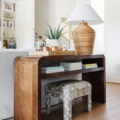 a living room with a table, stool and lamp