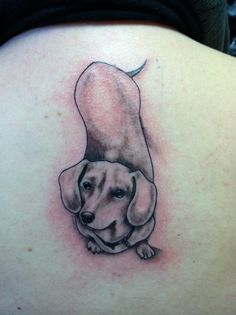 a woman's back with a dog tattoo on her shoulder and the image of a dachshund