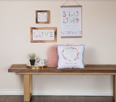 a wooden bench with two framed pictures on the wall above it and a coffee cup