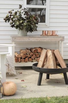 a fire pit sitting on the side of a house next to a pile of wood