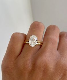 a woman's hand with a gold ring and a diamond engagement ring on it