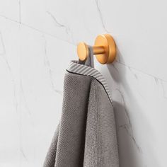 a towel hanging on the side of a white wall next to a yellow hook and two gray towels