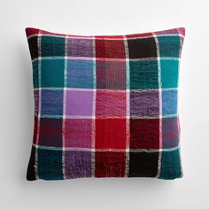 a multicolored plaid pillow on a white wall