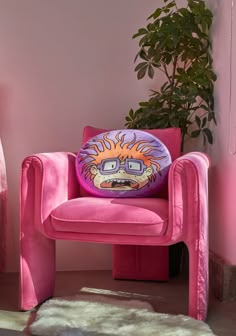 a pink chair sitting next to a potted plant