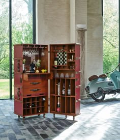 a scooter is parked next to an open cabinet with wine glasses on it