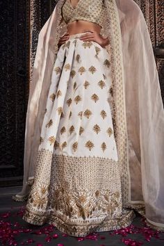 Ivory silk lehenga with an attached cancan and gold floral embroidery. Comes with a padded blouse and a dupatta.
Components: 3
Pattern: Embroidered
Type Of Work: Floral
Neckline: Deep V Neck
Sleeve Type: Sleeveless
Fabric: Silk
Color: Ivory
Other Details: 
Attached lining
Product Weight: 2 Kgs
Occasion: Wedding - Aza Fashions Off White Sharara For Reception With Traditional Drape, Off-white Sharara For Reception With Traditional Drape, White Silk Set For Reception, White Silk Sets For Reception, Designer Silk White Choli, Designer White Silk Choli, White Chanderi Dress With Gota Work, White Silk Sharara For Diwali, White Silk Sharara For Reception