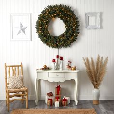 a christmas wreath is hanging on the wall next to a small table with presents under it