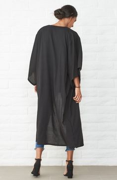 Eco friendly caftans and tunics inspired by the ocean, made on main street. Ethically sourced and locally made in Los Angeles. When we travel, we want clothes that take up minimum space but do maximum work. Meet the Kimono Wrap Duster in Black. It's a dress. It's a duster. It's a robe. It's a cover-up. This one does it all and we couldn't be happier! As a dress, two discreet buttons keep the wrap securely in place and give the dress an architectural drape. The removable self-tie belt can be add Black Long Sleeve Tunic For Vacation, Casual Black Kimono For Beach Cover-up, Black Tunic Cover-up For Spring, Casual Black Cover-up For Loungewear, Black Long Sleeve Tunic For The Beach, Black Long Sleeve Tunic For Beach, Spring Black Tunic Cover-up, Oversized Black Beachwear Cover-up, Casual Black Tunic For Vacation