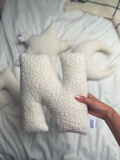 someone is holding two pillows in the shape of letters h and w on top of a bed