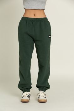 Elevate your athleisure style and feel like you're lounging on the go with our Hunter Green GH Jogger Sweatpants. The elastic waistband and tapered leg style allows you to feel secure and trendy. Complete with dual side pockets to keep your essentials close by. Pair with ur Hunter Green GH Cropped Hoodie to complete the set. Sporty Relaxed Fit Bottoms With Elastic Cuffs, Athleisure Joggers With Elastic Waistband, Athleisure Streetwear Joggers With Elastic Waistband, Athleisure Joggers With Elastic Waistband For Streetwear, Athleisure Sweatpants With Elastic Waistband For Streetwear, Sporty Green Pants With Elastic Side Panels, Athleisure Sweats With Elastic Waistband For Streetwear, Sportswear Joggers With Elastic Waistband For Loungewear, Loosely Fitted Jogging Sweatpants With Elastic Waistband