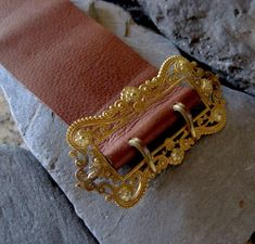 "This Victorian gold filled buckle has been sitting on my desk for 8 years. It is elegantly designed with a scroll and floral motif. I have wanted to make this into a bracelet but just couldn't find the time. I finally experimented with the leather. I chose a very supple leather that will probably darken from wearing and the oils in your skin giving it natural marks. For my first leather bracelet, I am happy with how it came out. The holes are not perfectly aligned but they look pretty good. Wha Elegant Engraved Gold Belt Buckles, Elegant Gold Engraved Belt Buckles, Classic Formal Jewelry With Brass Hardware, Formal Gold Engraved Belt Buckles, Luxury Gold Adjustable Belt Buckle, Luxury Adjustable Gold Belt Buckle, Elegant Adjustable Belt Buckles With Brass Buckle, Elegant Brown Belt Buckles With Brass Hardware, Elegant Adjustable Belt Buckle With Brass Detail