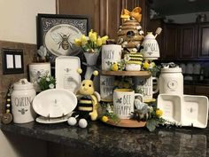 a kitchen counter topped with lots of plates and cups covered in bees, flowers and honeybees