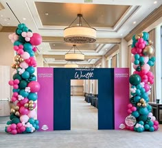 an entrance decorated with balloons and streamers for a corporate event or conference center in pink, blue, and gold