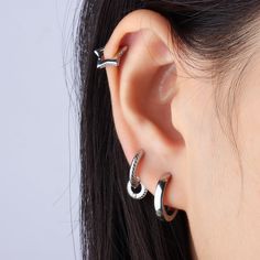 a close up of a person wearing two different types of ear piercings on their ears