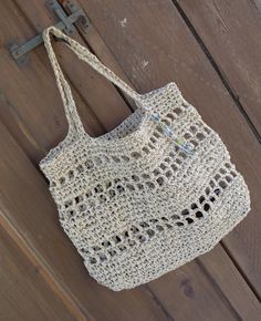 a white crocheted bag hanging on a wooden wall with a hook in it