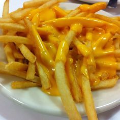 cheese fries on a plate with ketchup drizzled over them