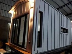 the tiny house is being built on top of a trailer in an industrial building with windows and doors